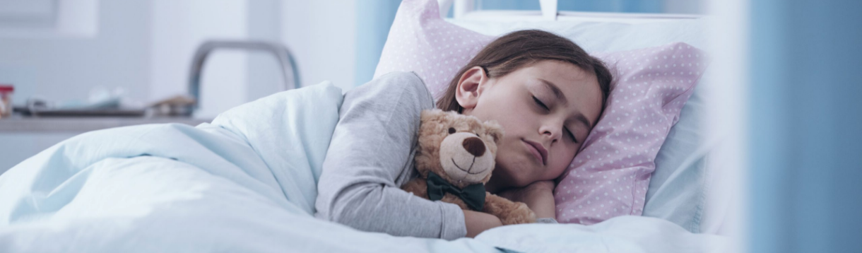 Niña durmiendo plácidamente abrazada a su osito de peluche