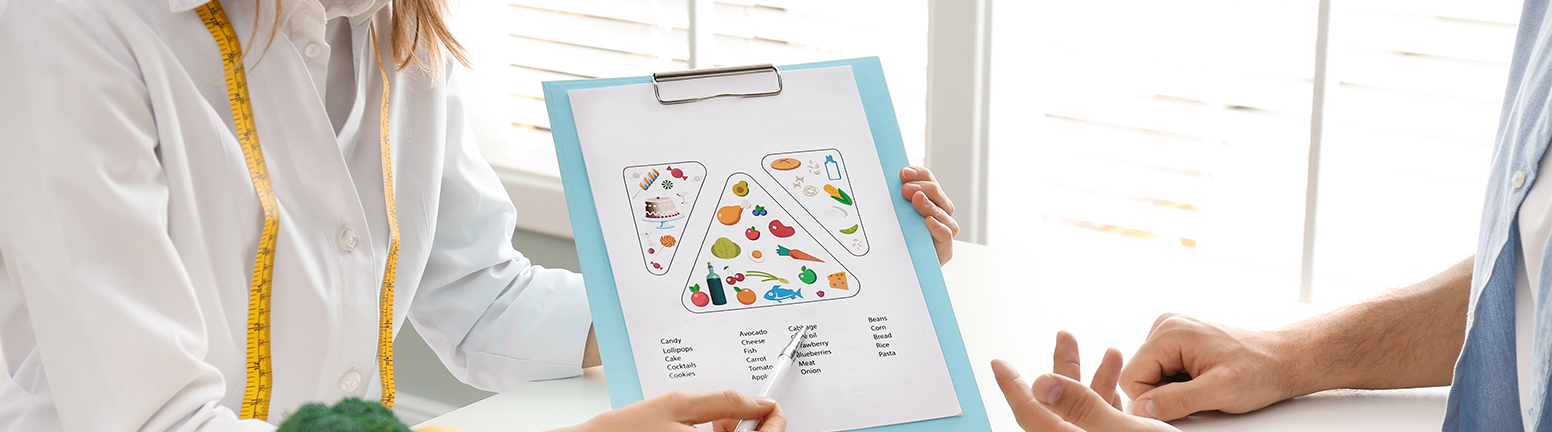 Doctora mostrando pirámide nutricional a paciente Doctora mostrando pirámide nutricional a paciente